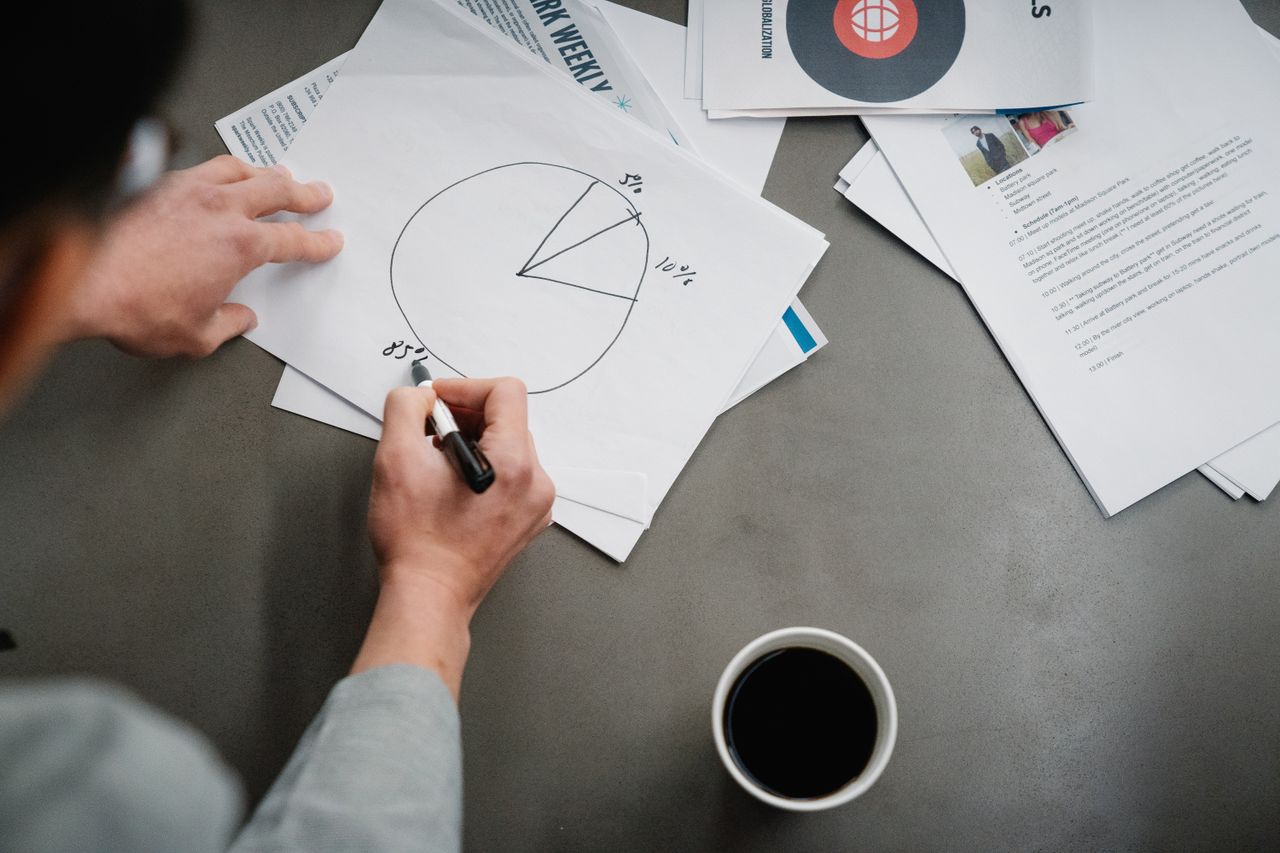 Services Man drawing a pie chart on paper with coffee, representing business planning and analysis.
